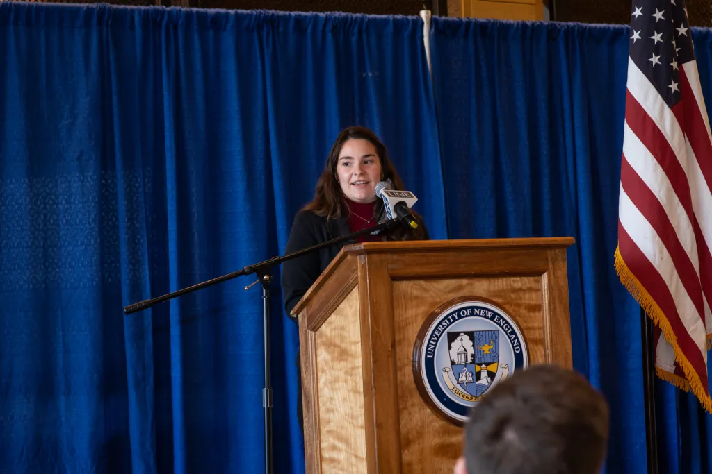 Ashley Roy stands at the podium and speaks to the crowd