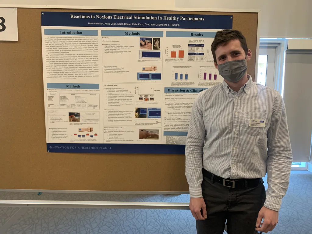 Male student stands in front of poster