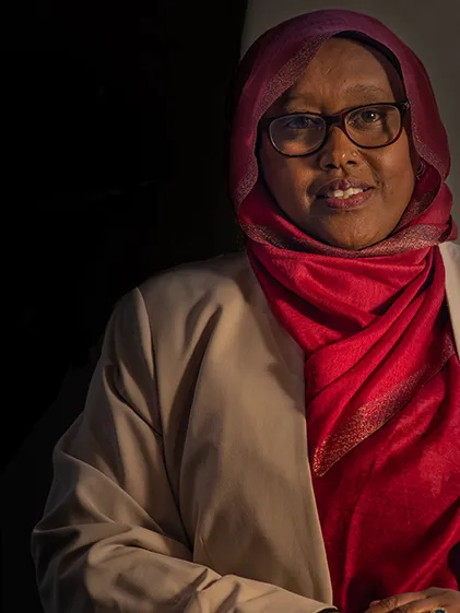 Deqa Dhalac poses for a photo against a dark backdrop