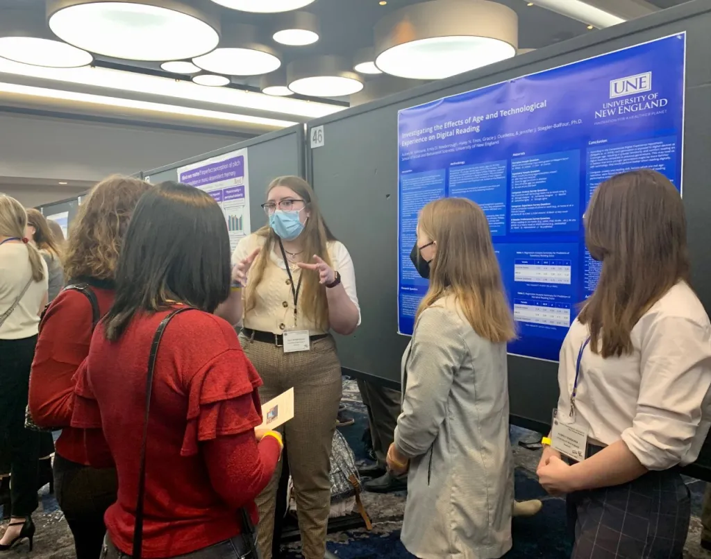 Emily Newborough presents a poster to a group of people at the EPA conference