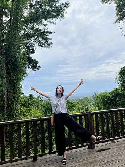 Celia Larson poses in front of a rainforest view