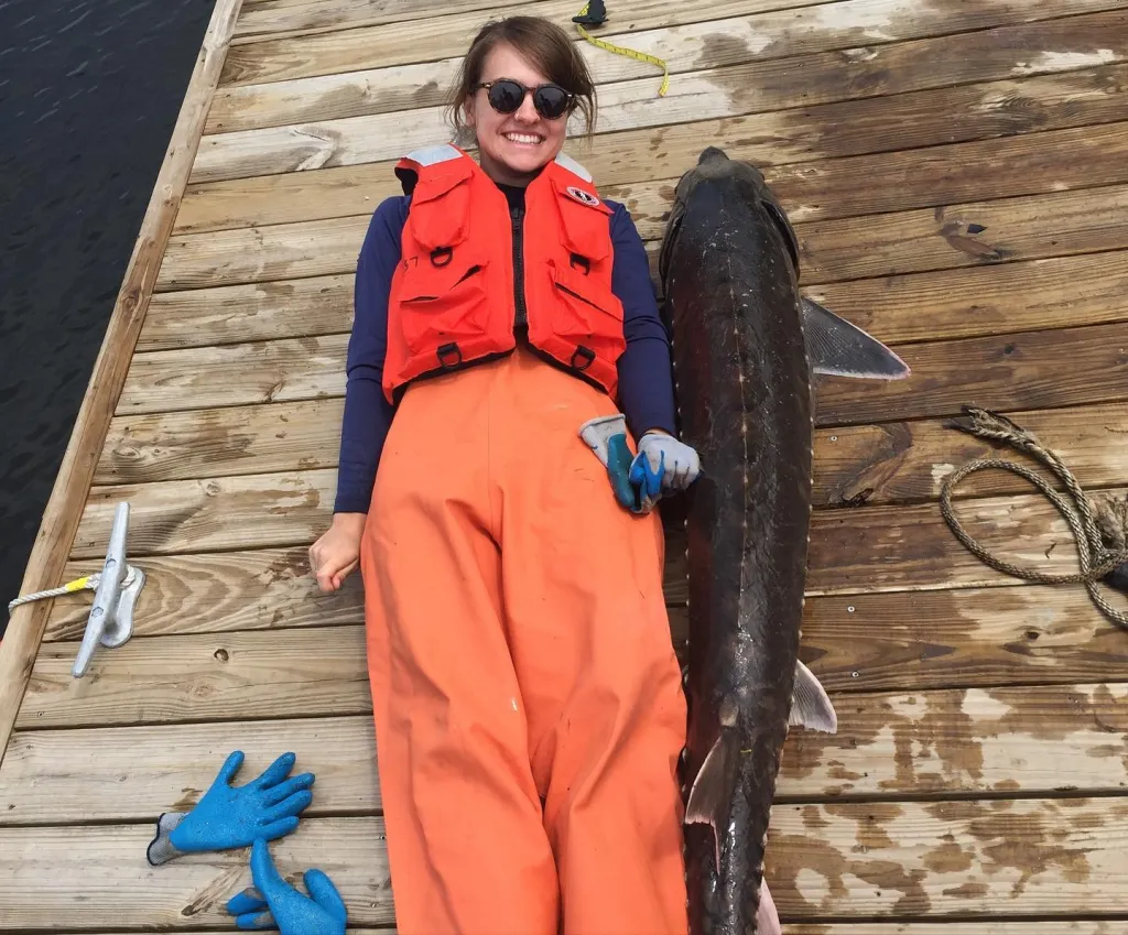 U N E student Abigail Hayne lays on a dock next to a fish as long as she is