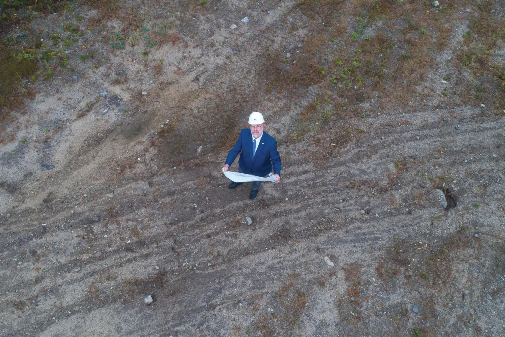 Aerial view of Al Thibeault reviewing architectural documents over the spot of an upcoming U N E building