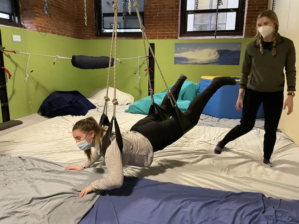 Two female students use a hanging tool for children at an occupational therapy clinic
