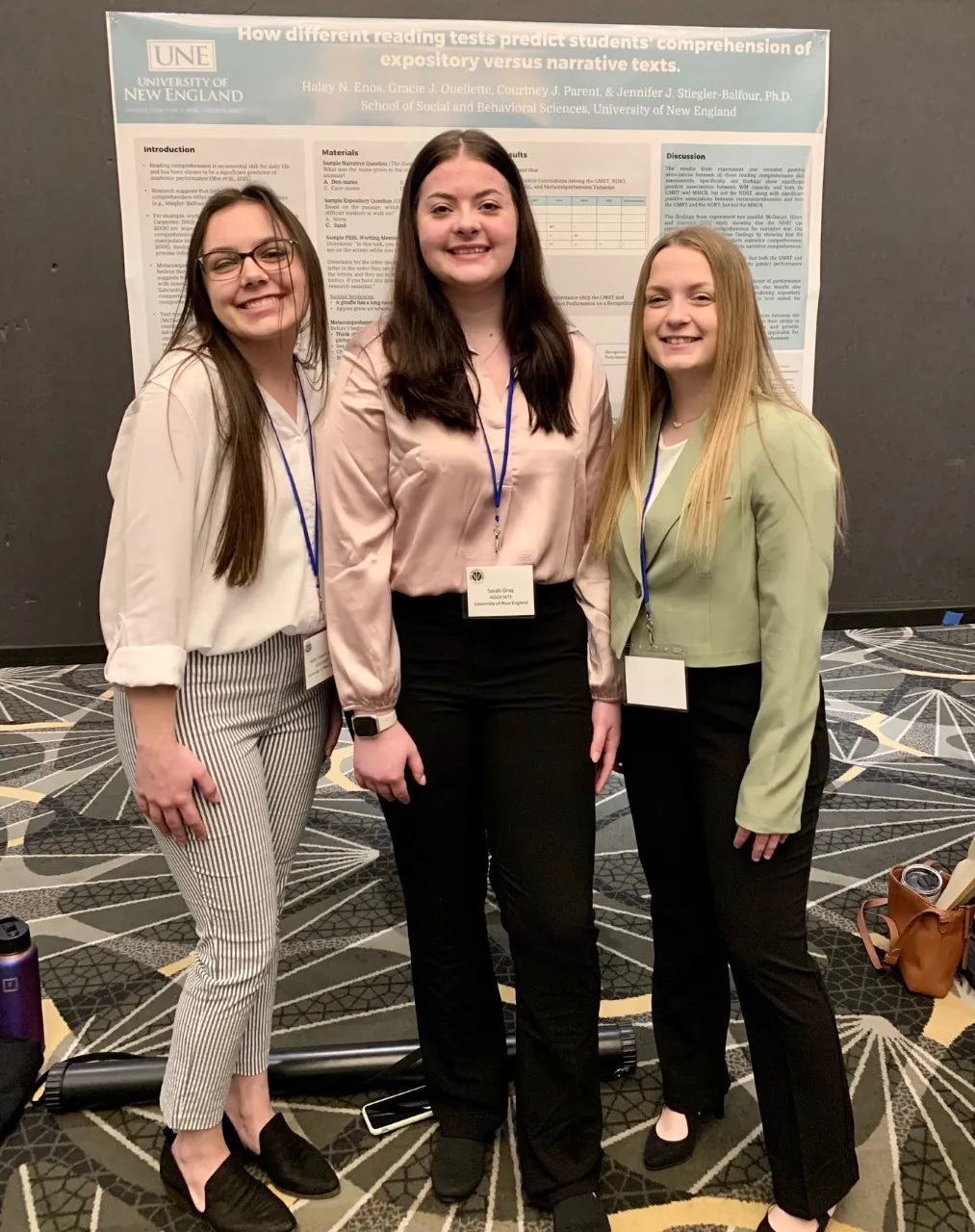 Haley Enos, Sarah Gray, and Gracie Ouellette pose in front of their poster
