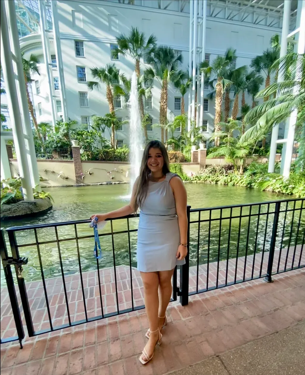Morgan Desmond poses in front of an artificial oasis, with a pond and trees, inside a convention center 