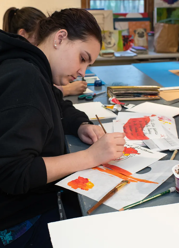 A student watercolors pages as part of a bookmaking project