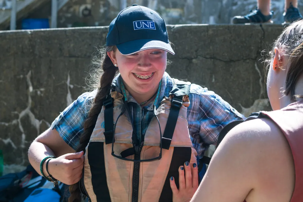 A student smiles as they put a life vest on
