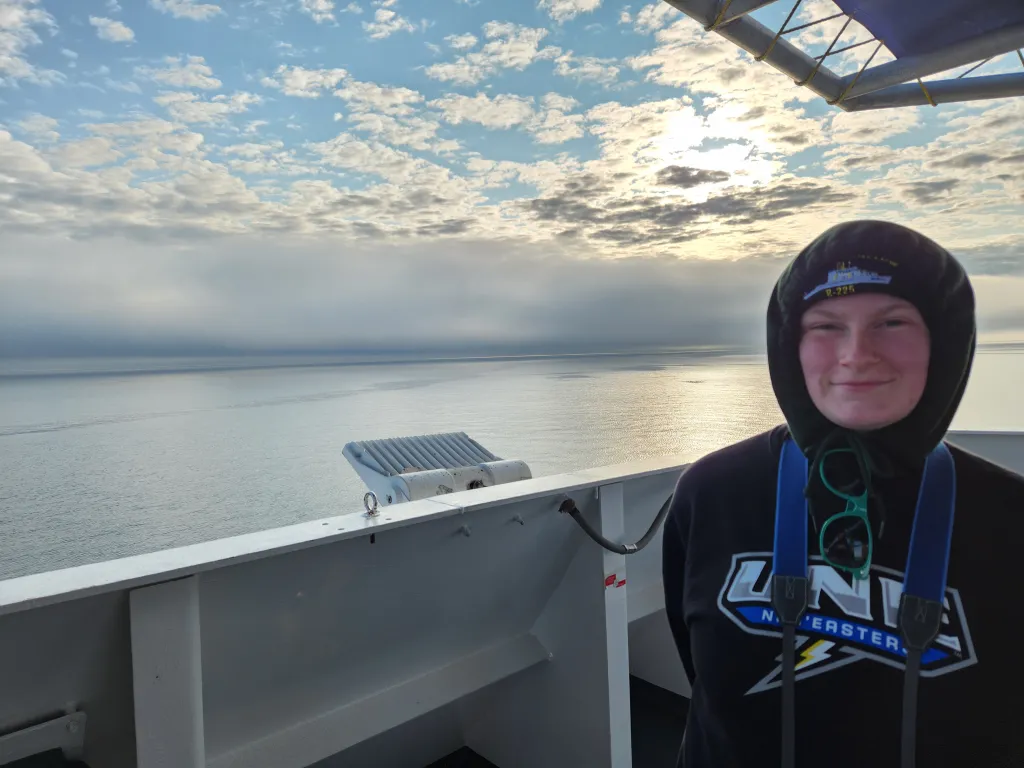 Kenzi Kimball bird watching with binoculars on NOAA research vessel