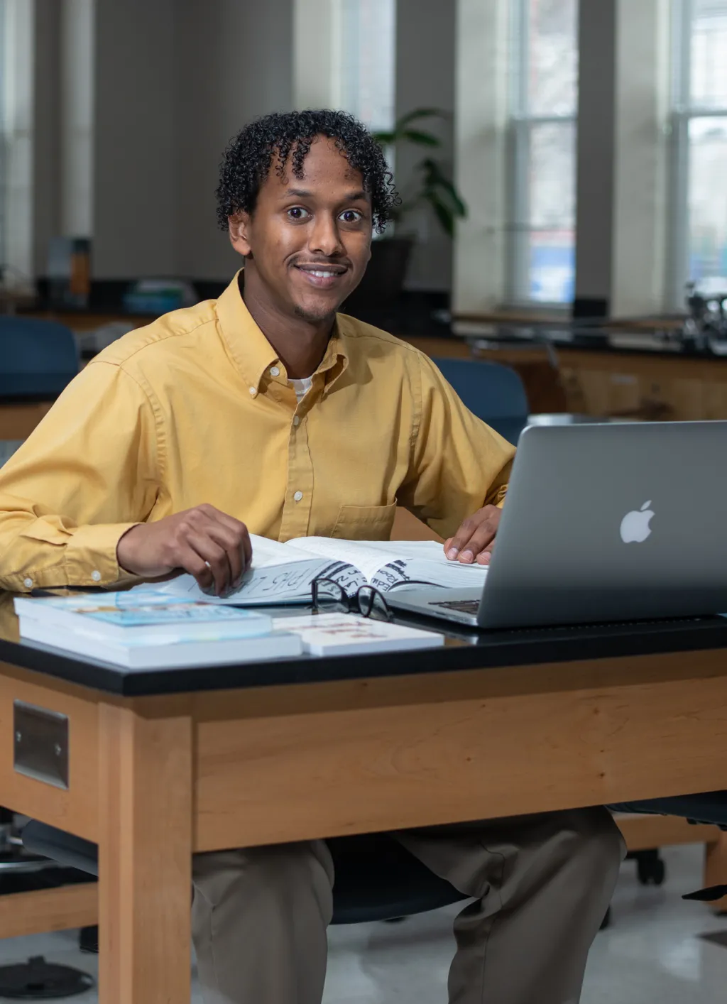 A U N E online student studies with open books at their laptop in a coworking space