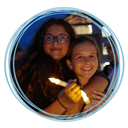 Two students hug while holding fake candles during First Night