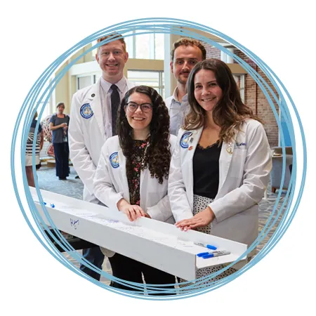 Four C O M students stand in front of a ceremonial beam they signed to celebrate the upcoming Harold and Bibby Alfond Center for Health Sciences on the Portland Campus