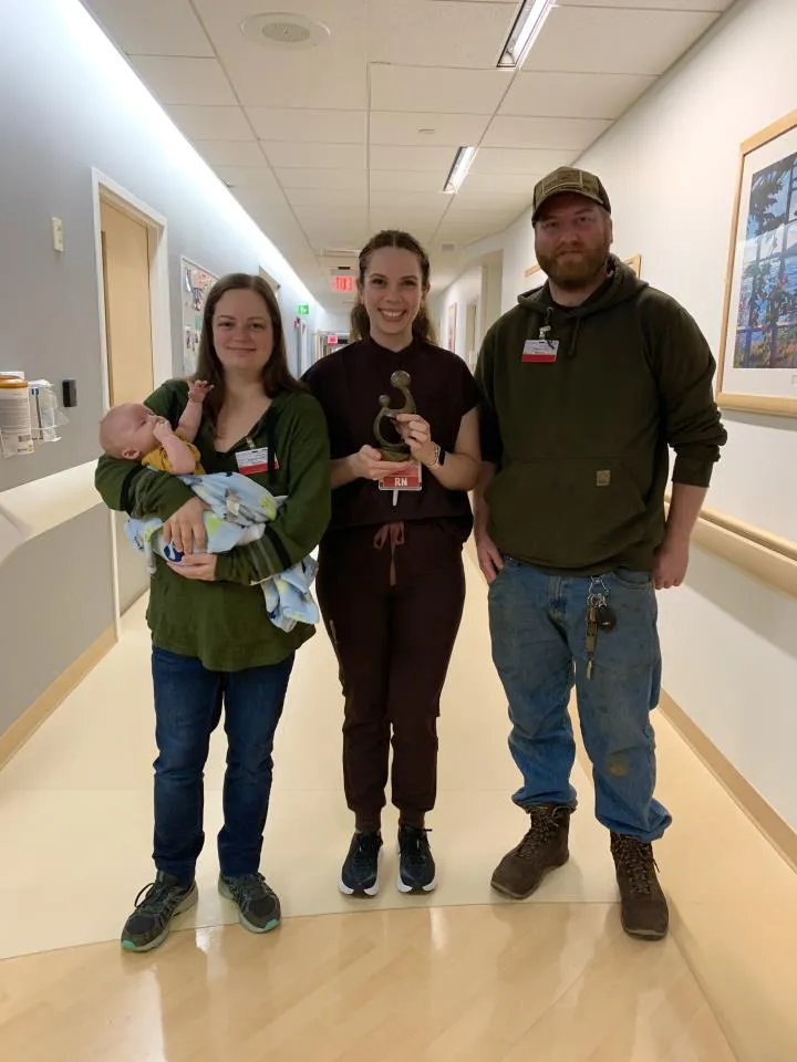 A nurse poses with two patients plus a baby