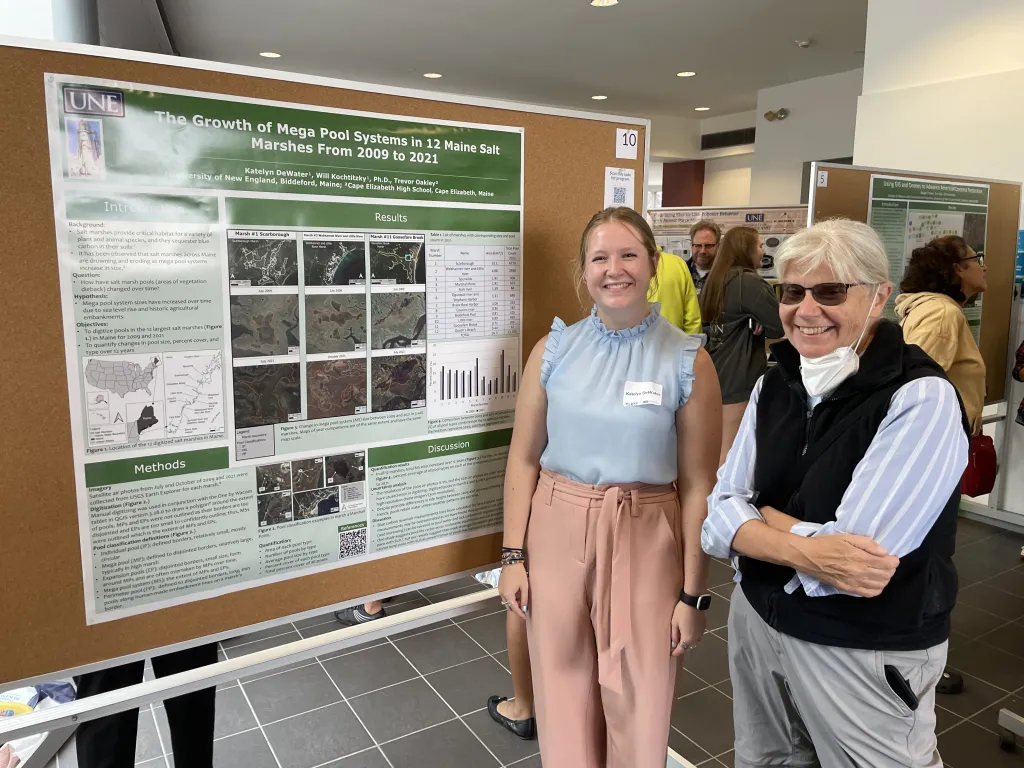 DeWater poses in front of her research poster with a spectator