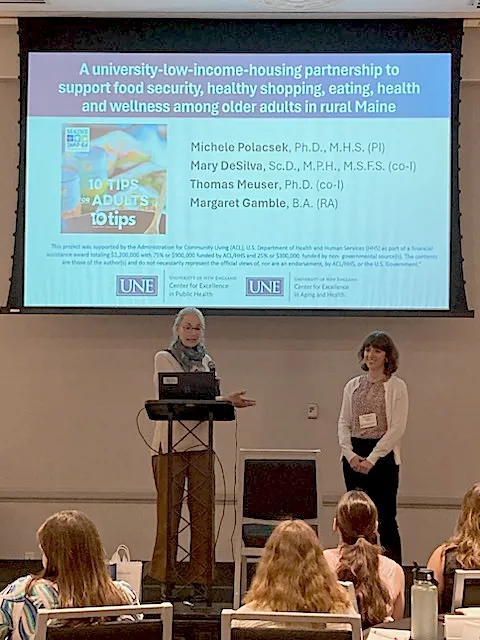 Michele Polacsek and  Margaret Gamble stand in front of people presenting research