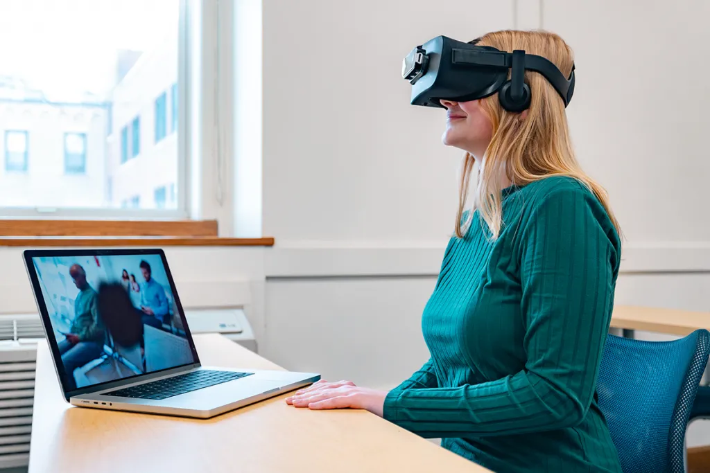 A Gerontology student wears a V R headset while using a virtual program that mimics having macular degenertion