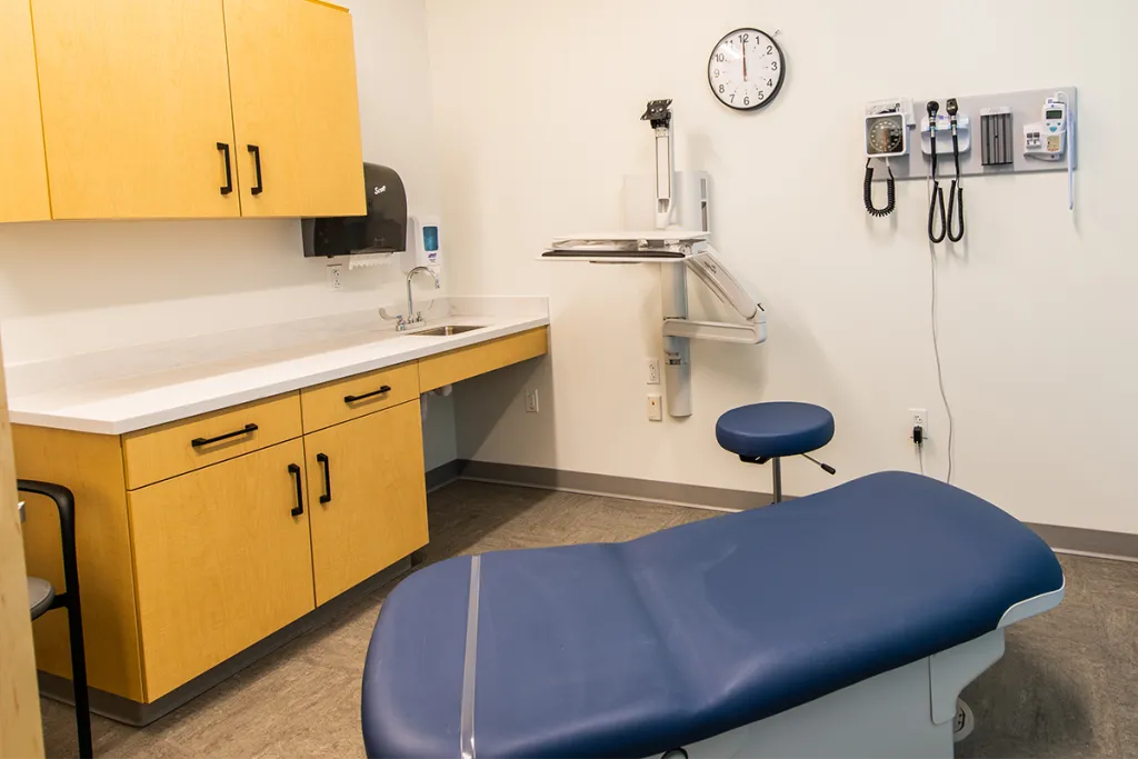 An exam room setup with examination table, cabinetry, and clinical tools