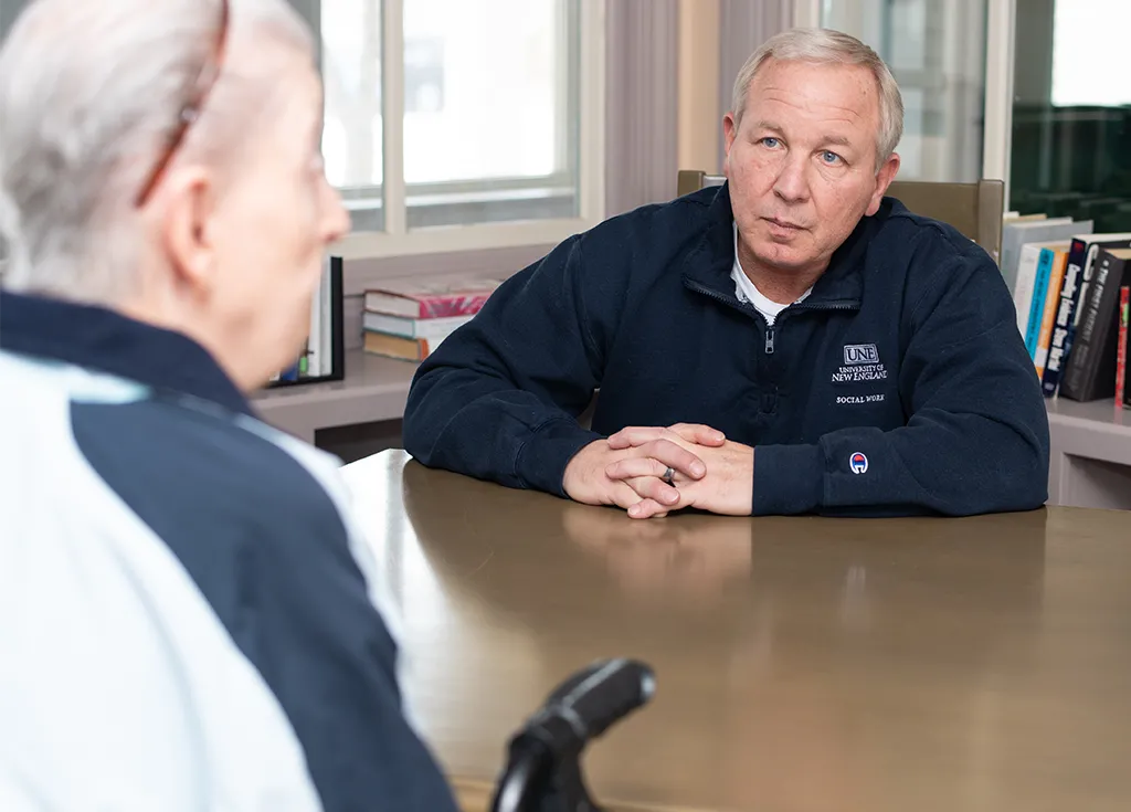 A social work student talks with an elderly patient