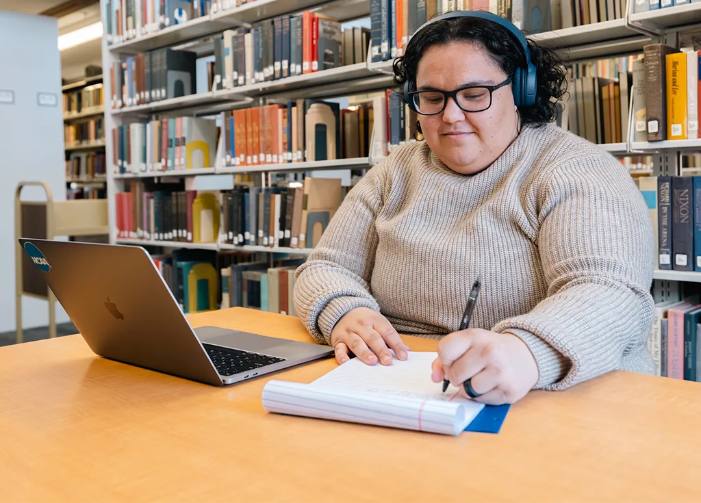A student at their laptop in a library setting