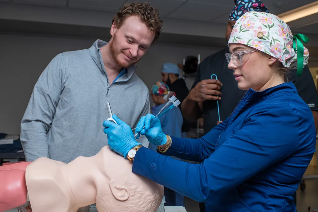Three nursing anesthesia students practice intubating a patient simulator