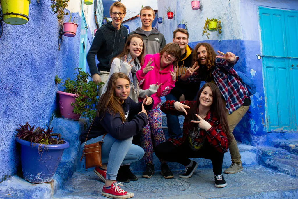 A group of students pose together in front of blue Moroccan buildings