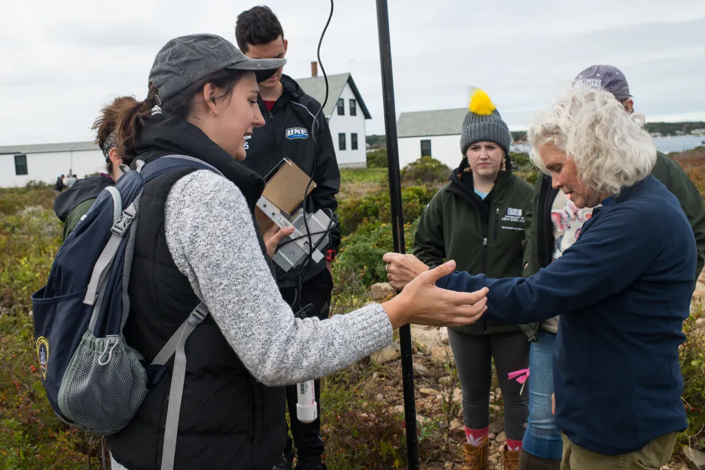 Instructor Pam Morgan and students install a monitor to collect wind data on Goat Island