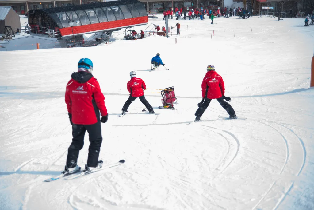 Currier steers the bucket seat for a winter sports program participant.