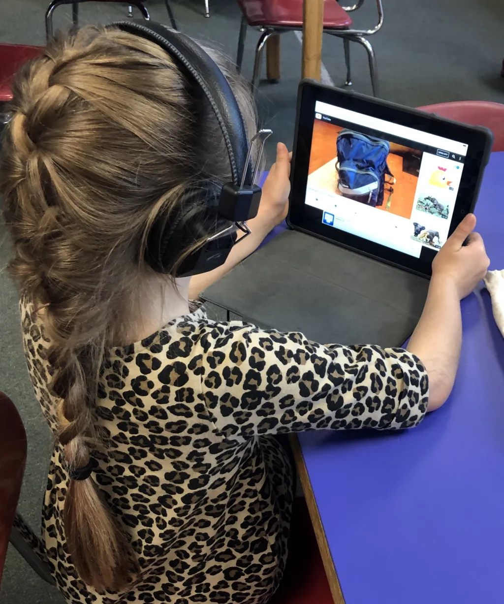 Students scan a QR code using an iPad and listen to the child’s story through headphones