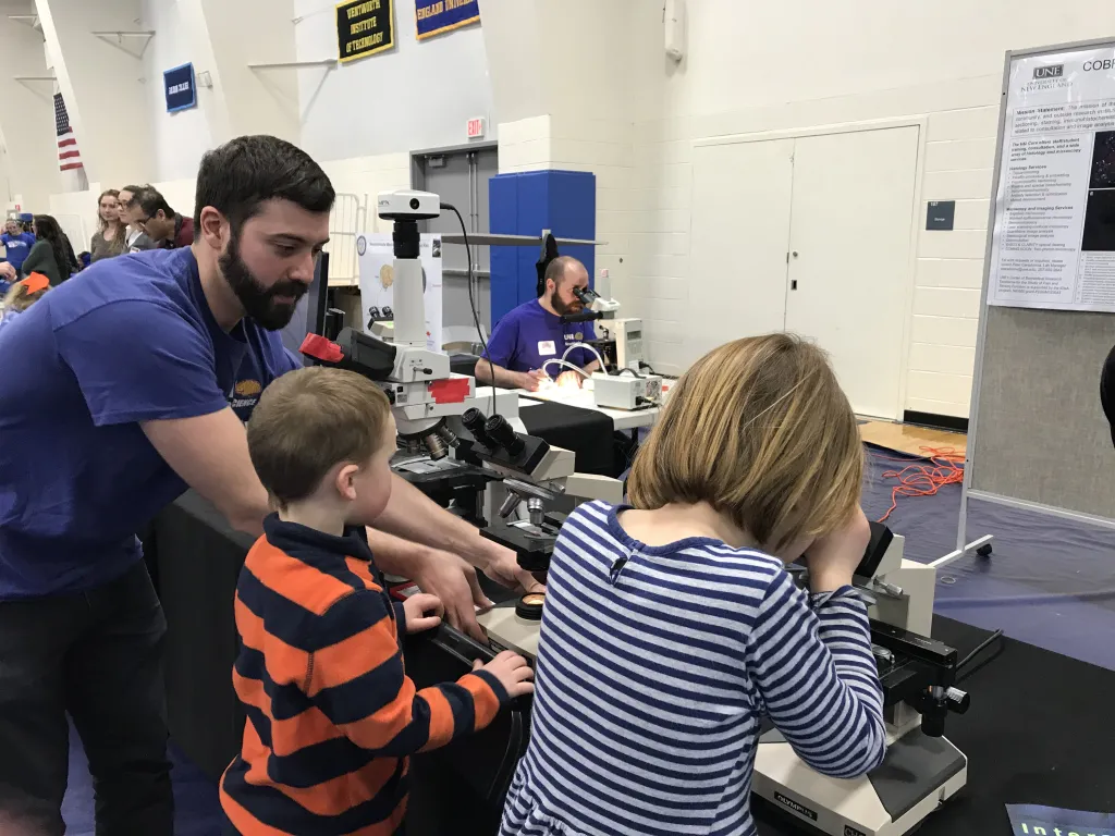 Peter Caradonna, manager, COBRE Histology and Imaging Core, assists children with some microscopes