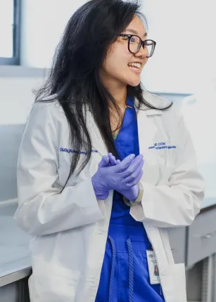 A student in a white coat and dark blue scrubs