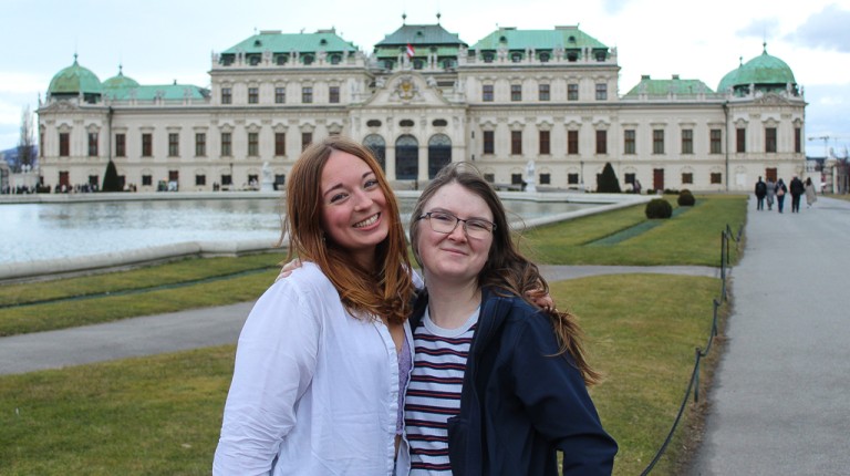Two U N E students pose in front of the Belvedere Palace in Austria