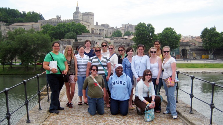 A group of U N E students pose in front of a castle