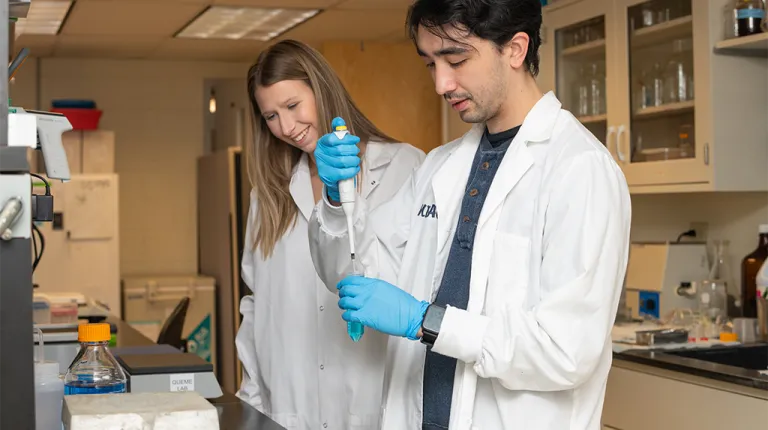 Two students in white coats in a lab