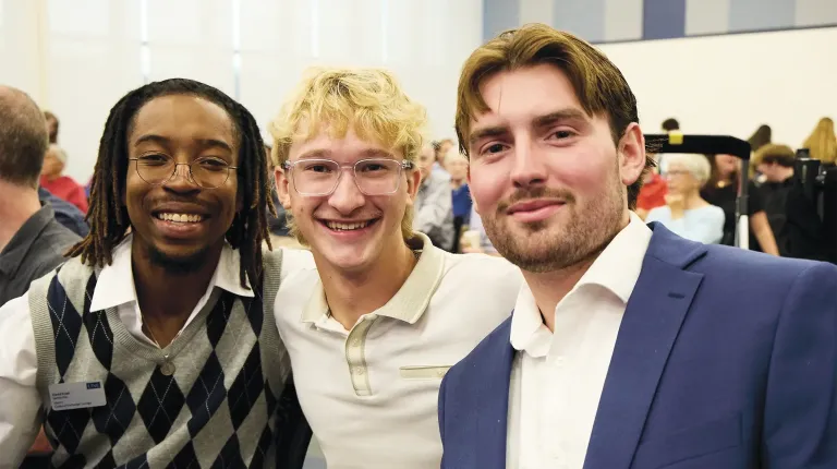 Three attendees smile for the camera at the President's Forum event.