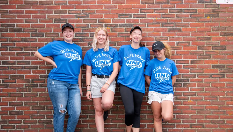 Student helpers pose against a brick wall