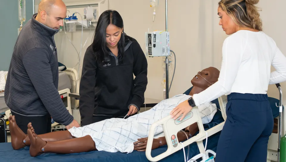 A group of health students practice diagnosing on a patient simulator in the Simulation Lab