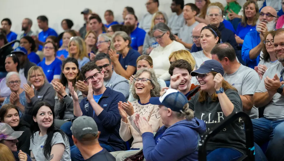 Smiling and laughing U N E employees fill the bleachers in the Alfond Forum during a Fall Assembly event