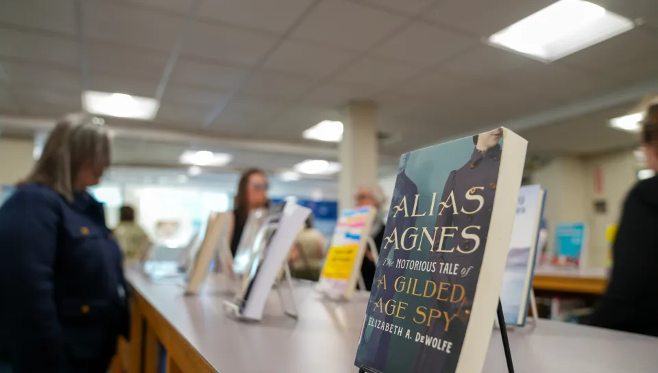 a book in the foreground and people milling in the background