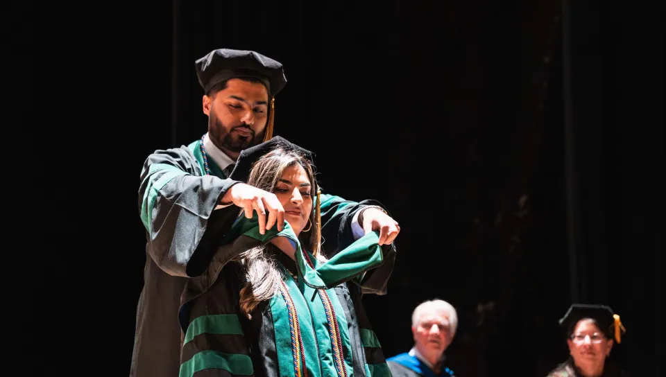 Hammad Sadiq, hoods his sister, Hafsa, with the Doctor of Osteopathic Medicine stole