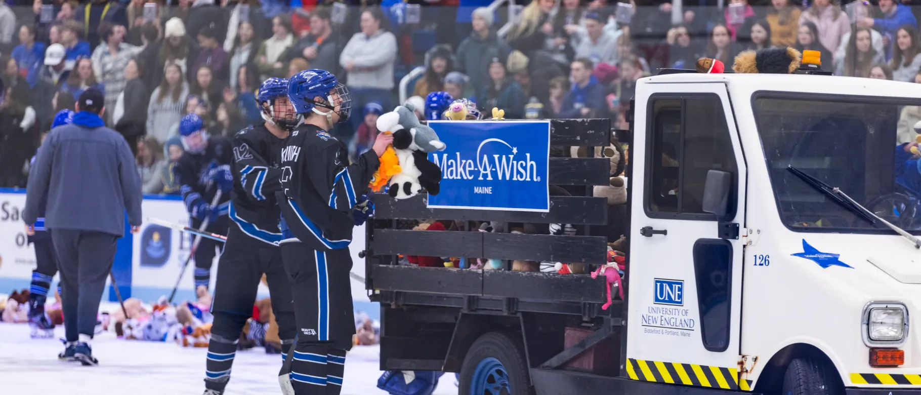 UNE men's hockey players load teddy bears onto a truck bed during the annual Teddy Bear Toss
