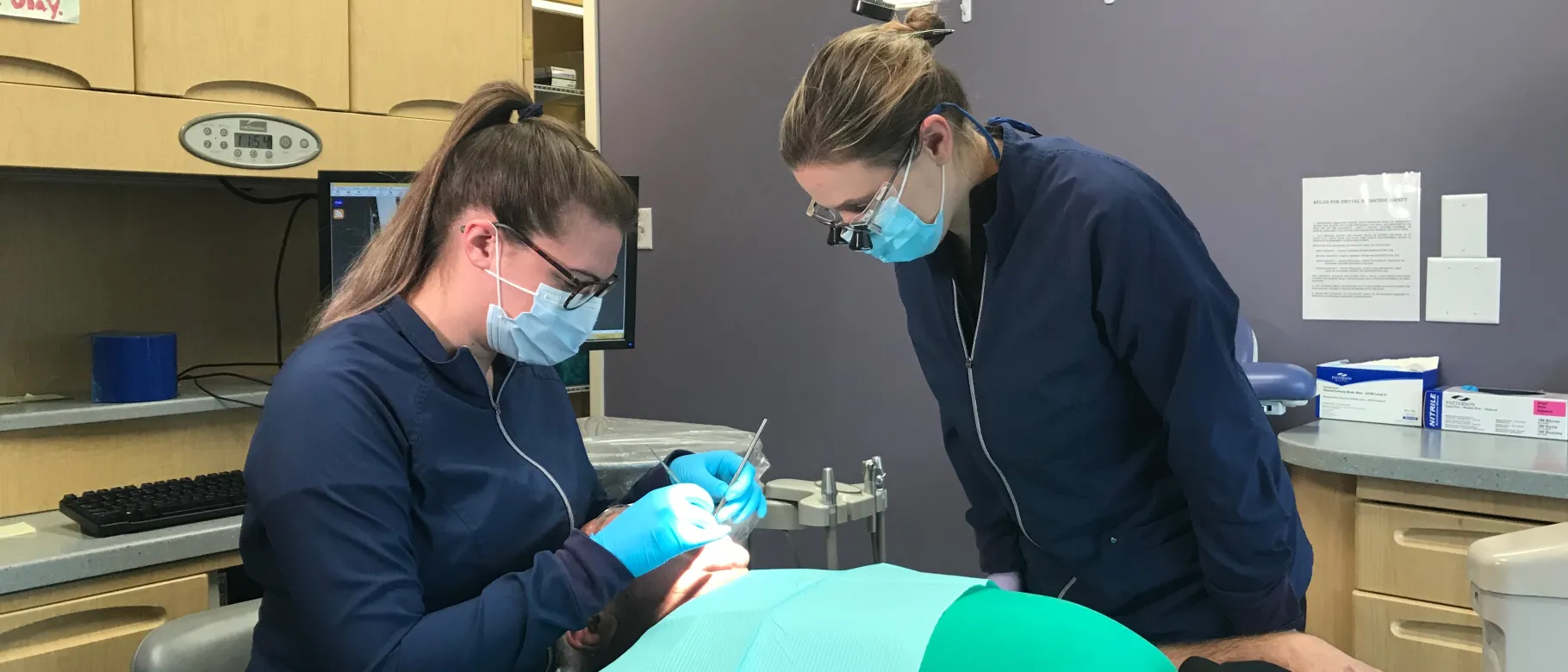 UNE student Kailee Williams works on a patient as Dr. Audra Boynton looks on