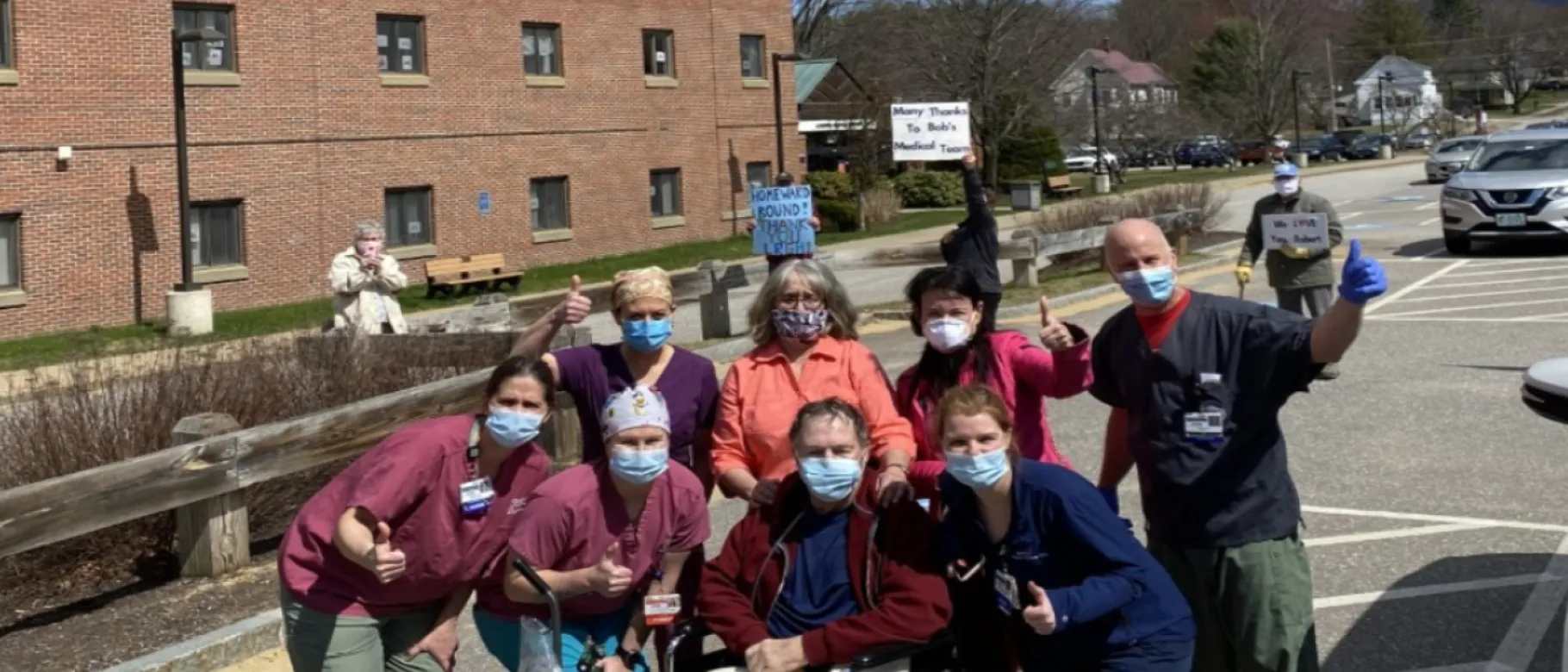 Lisa O'Kane (front row, second from left) with patient Robert White and hospital staff. White's family with signs in background.