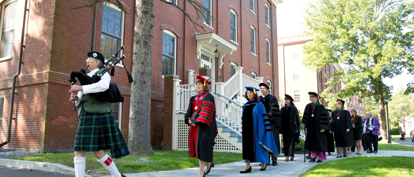 A bagpipe player leads U N E President Danielle Ripich and others across U N E's Portland Campus during convocation 