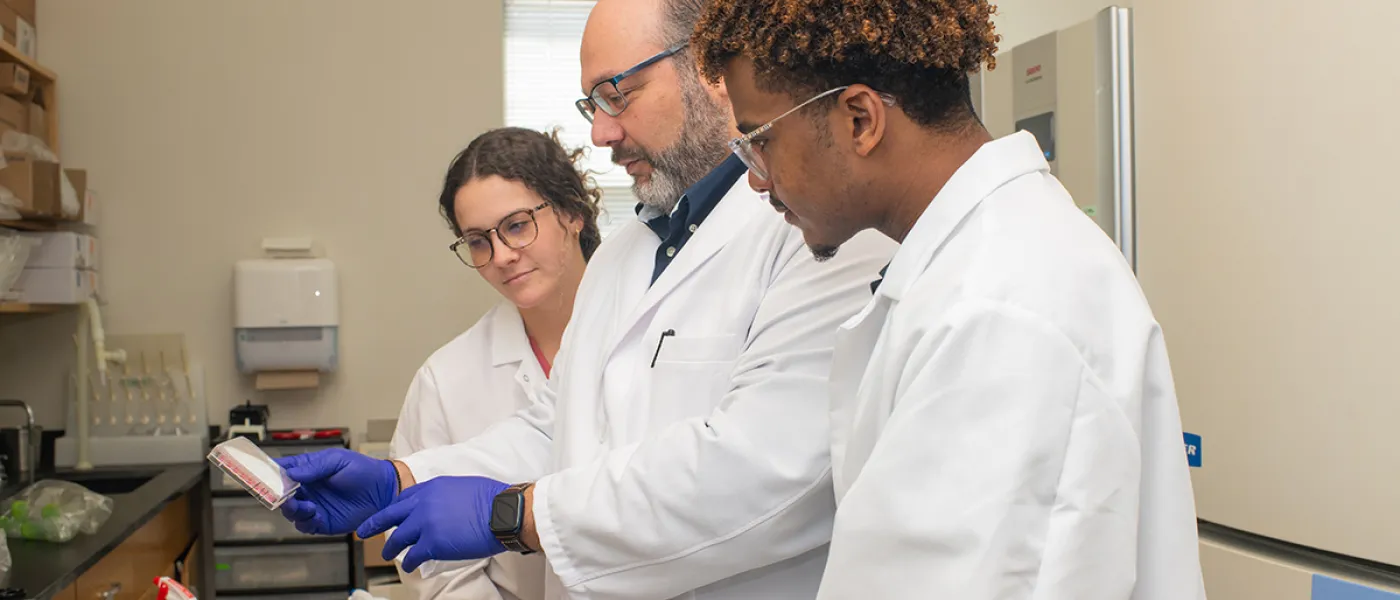 Two students and a professor reviewing part of a lab
