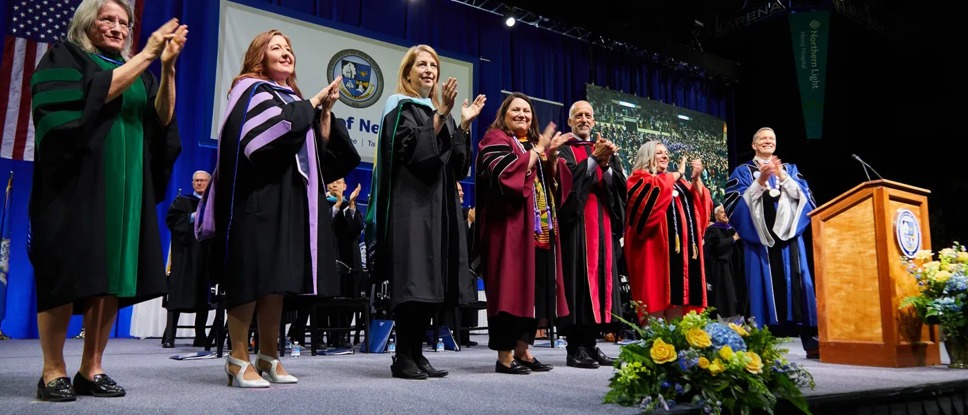 President James D. Herbert and the deans of the University of New England clap on the stage in congratulations to all the 2024 UNE graduates.
