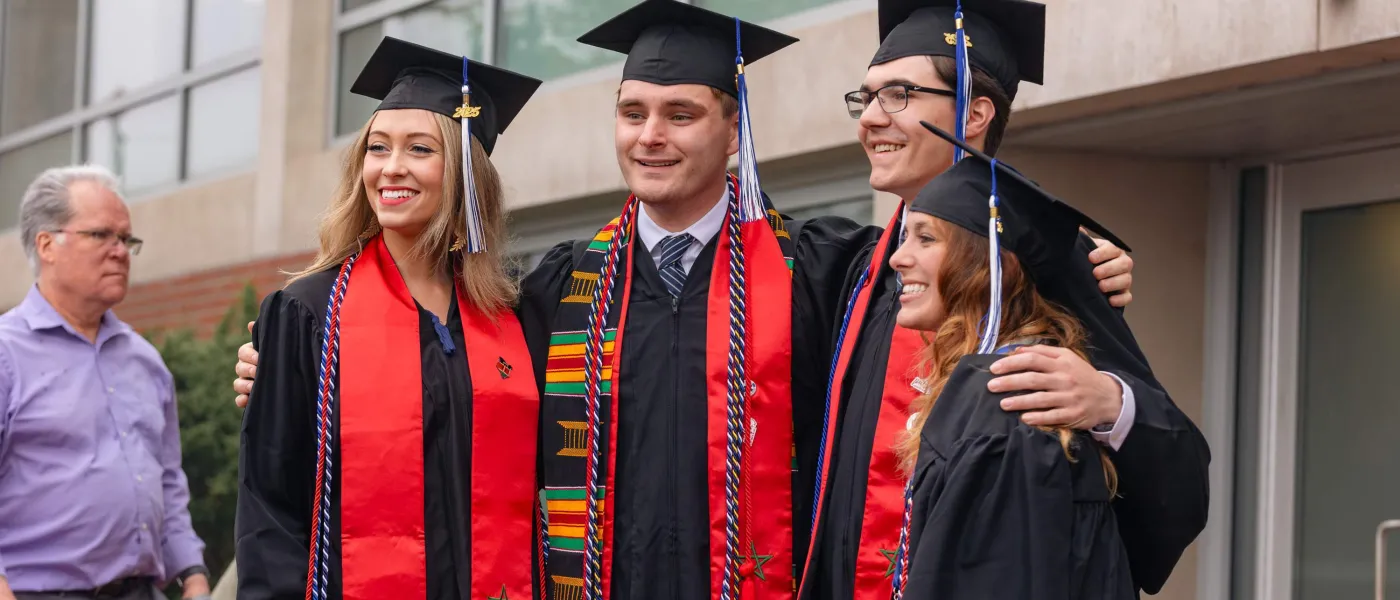 Graduates pose in their caps and gowns outside the Cross Insurance Arena in Portland