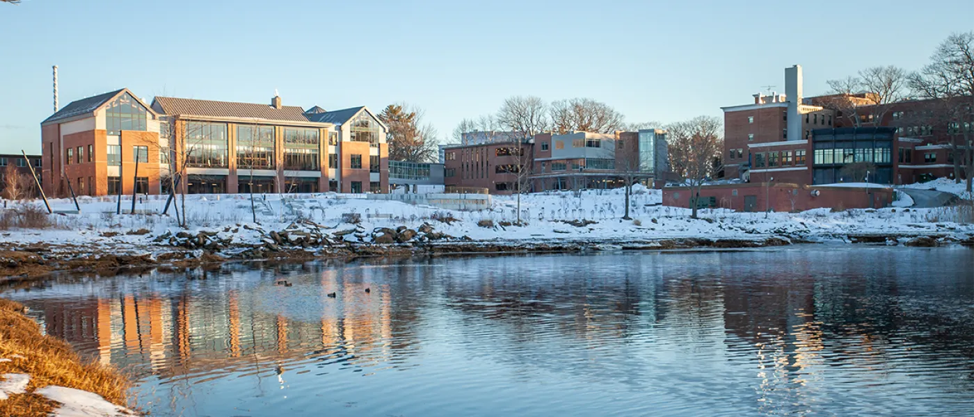 A brick building sits behind water surrounded by snow