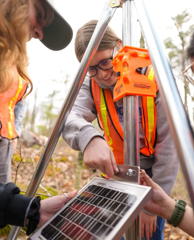UNE students assemble components of a weather station in UNE's research forest