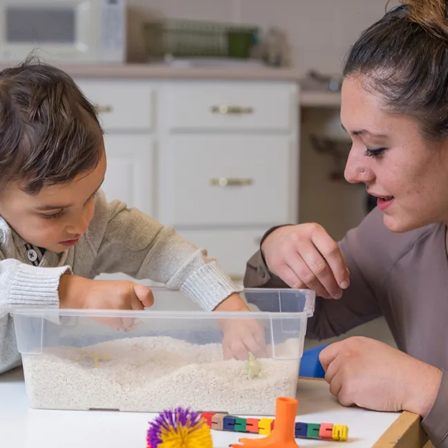 a u n e student works with a child using a sensory table