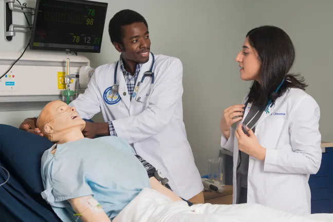 two students work on a patient simulator